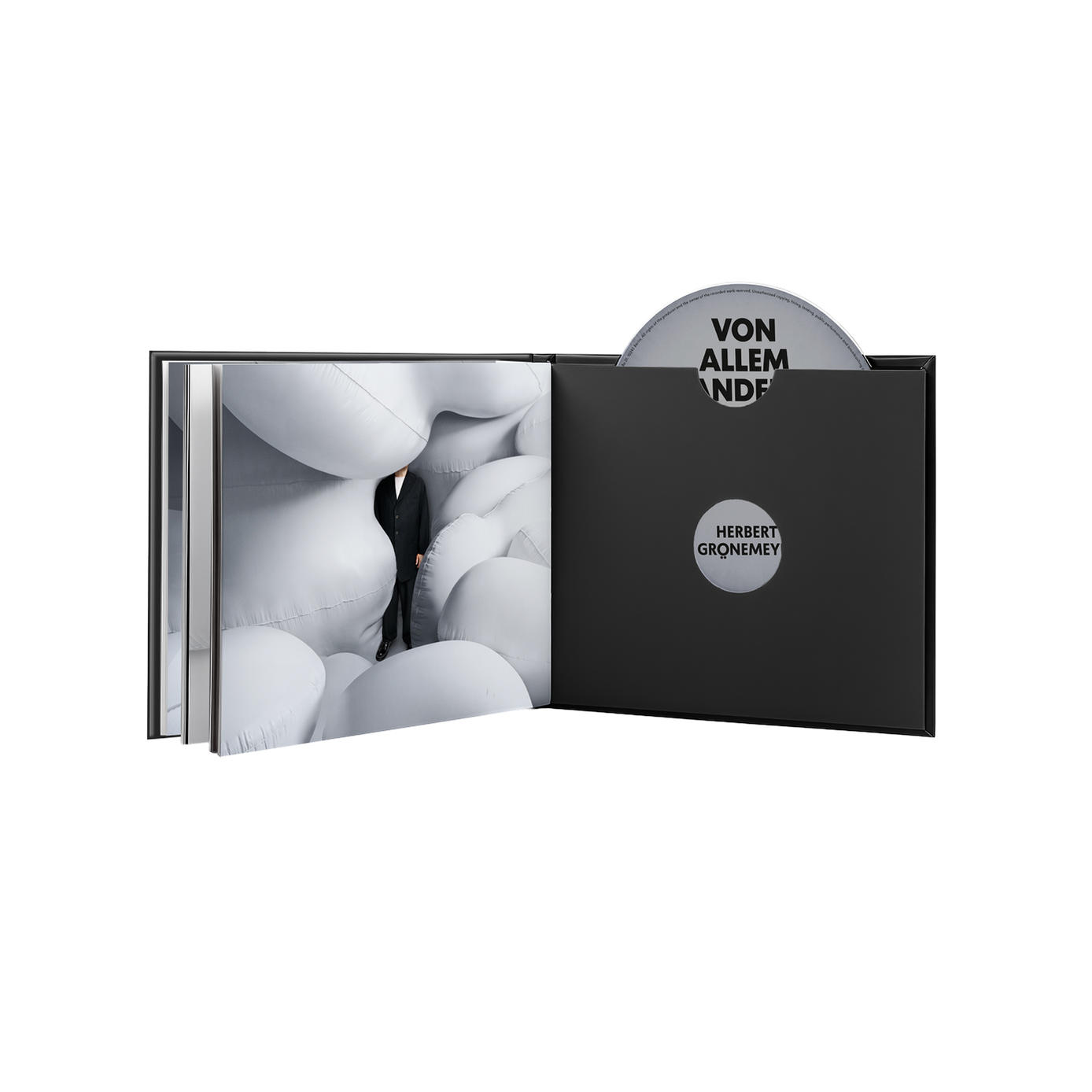 Offenes Buch mit CD. Mann in schwarzem Anzug steht inmitten weißer, aufgeblasener Formen. Schwarzer Koffer hat CD mit Text. Albumcover.