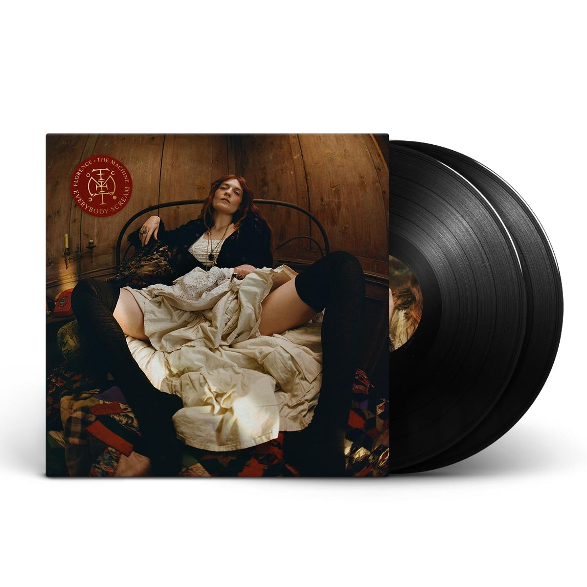 Florence + The Machine Albumcover. Frau im Bett, Album teilweise sichtbar. Vinyl-Schallplatten sichtbar. Schwarze Strumpfhosen, weißes Kleid, Holz-Hintergrund.