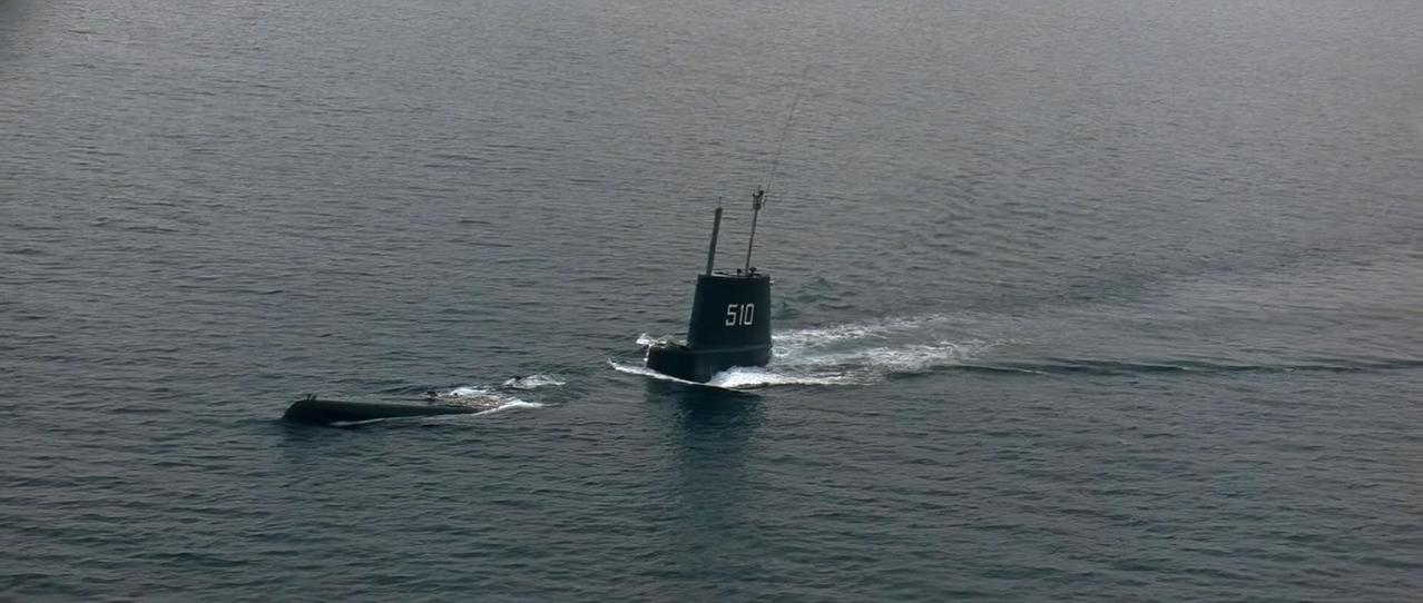 Zwei U-Boote auf See. Eines taucht auf und zeigt die Nummer 510. Das andere ist untergetaucht, nur seine Form ist sichtbar.