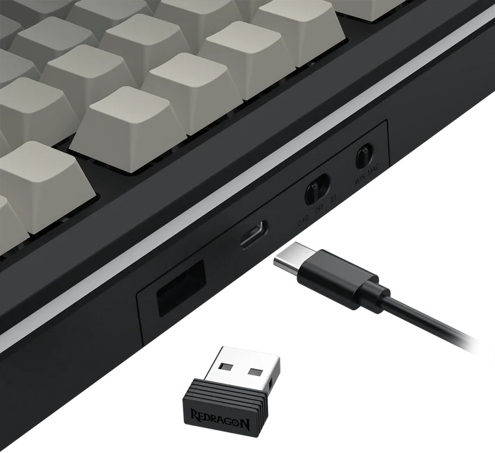 Czarna klawiatura z beżowymi klawiszami. Obok kabel USB-C i odbiornik USB Redragon. Klawiatura posiada porty połączeniowe.
