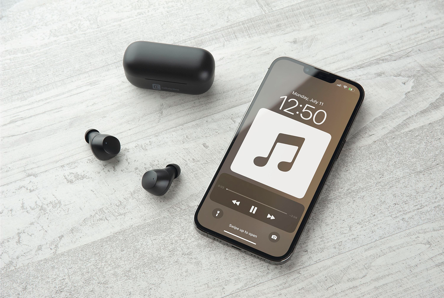 Auriculares negros, estuche de carga y smartphone mostrando interfaz de reproductor de música en madera.