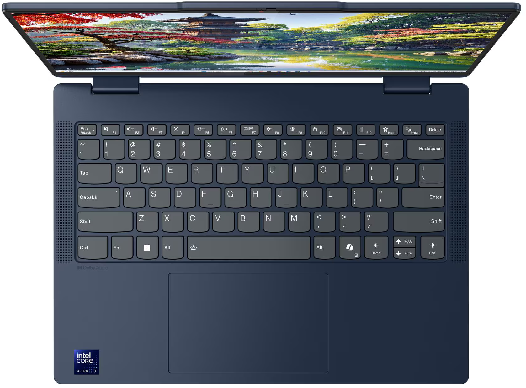 Egy sötétkék laptop nyitva, a billentyűzet látható. A képernyő egy tájat mutat fákkal és vízzel.