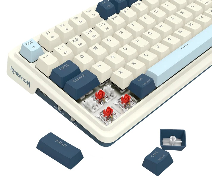Zbliżenie klawiatury mechanicznej. Klawisze są w kolorze złamanej bieli i granatowym. Widoczne czerwone przełączniki. Zawiera klawisze Shift i Ctrl.