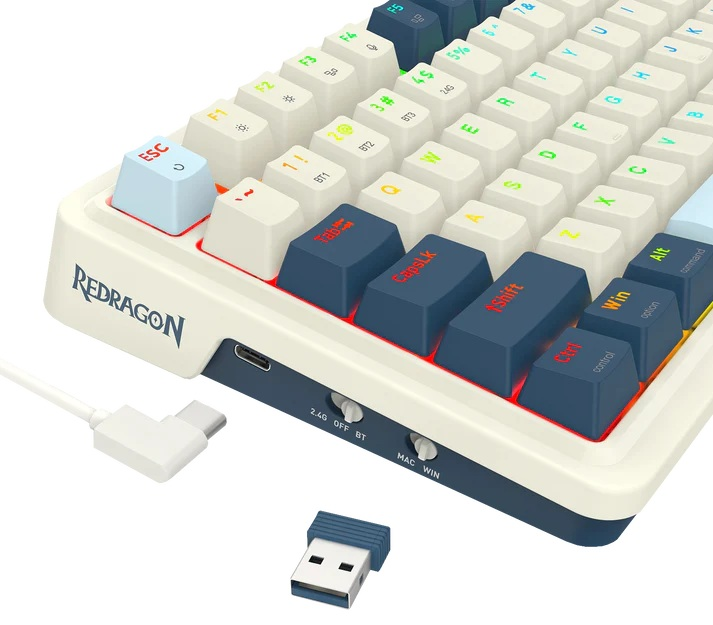 Zbliżenie klawiatury mechanicznej z białymi i niebieskimi klawiszami. Klawiatura ma markę 'Redragon'. Obecny jest również klucz USB i kabel.