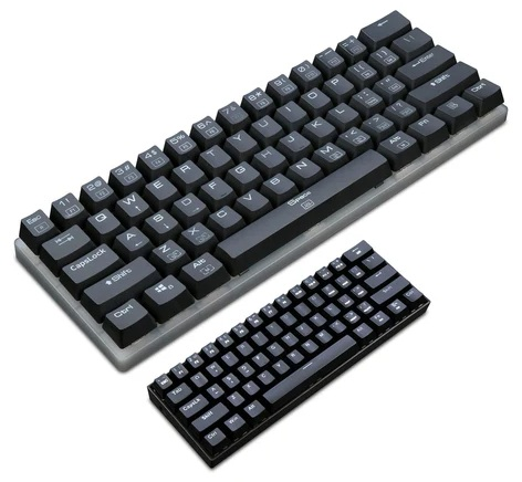 Dwie czarne klawiatury, duża i mała, na białej powierzchni. Klawisze mają białe litery i symbole.