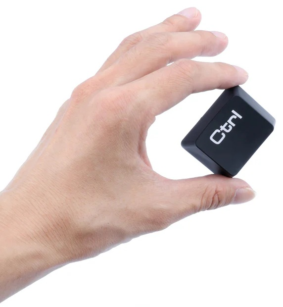 Dłoń trzyma czarny klawisz Ctrl na białym tle. Klawisz jest pochylony, z białym napisem 'Ctrl'.