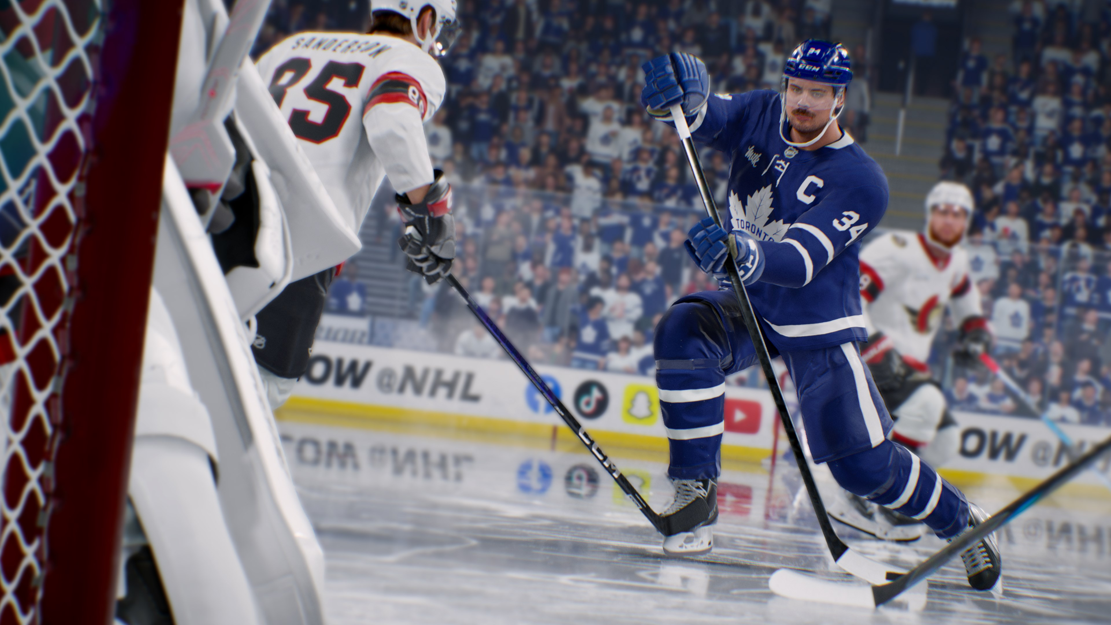 Ein Hockeyspieler in blauem Trikot mit dem Maple Leafs-Logo fährt während des Spiels auf den Puck zu. Ein Spieler in weißem Trikot ist in der Nähe.
