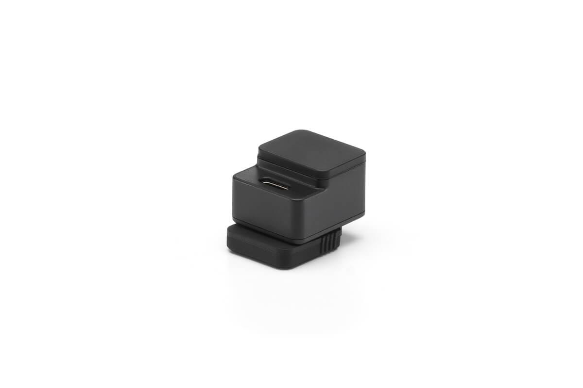 Ein schwarzer rechteckiger Adapter mit einem USB-Anschluss. Er hat eine Basis und einen oberen Abschnitt. Der Hintergrund ist weiß.