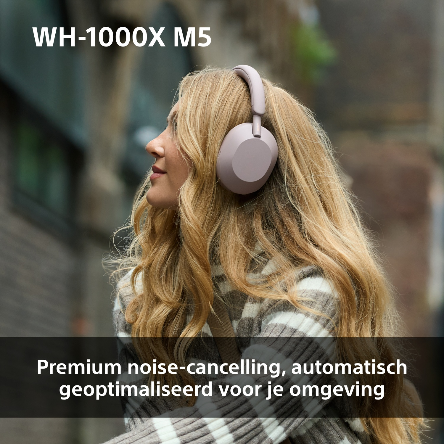 Une femme aux cheveux blonds porte un casque. Le texte 'WH-1000X M5' est visible. L'arrière-plan est flou avec des bâtiments.
