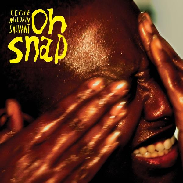 Egy személy arcának és kezeinek közeli képe. A szöveg szerint 'Oh Snap' és 'Cécile McLorin Salvant'. A személy mosolyog, a szeme részben takarva.