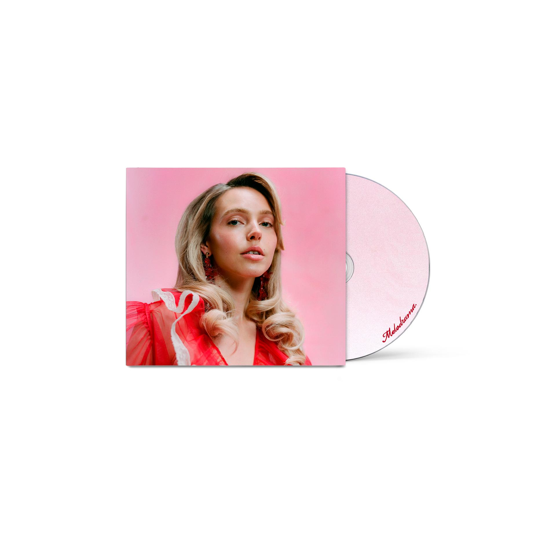 Eine Frau mit blonden Haaren in einem roten Kleid vor einem rosafarbenen Hintergrund. Eine CD mit „Melodrama“ ist im Bild.