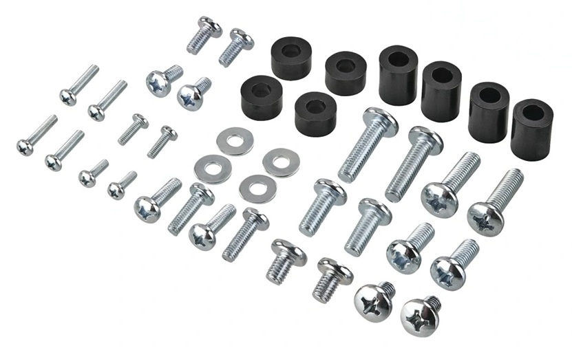 Różne śruby, podkładki i czarne cylindryczne dystanse ułożone na białej powierzchni. Metalowe elementy są błyszczące.