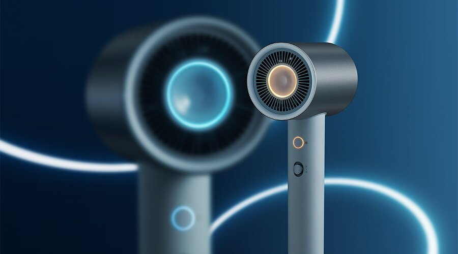 Nowoczesna srebrna suszarka do włosów z pomarańczowym, świecącym środkiem, niebieskim tłem i drugą, rozmytą suszarką.