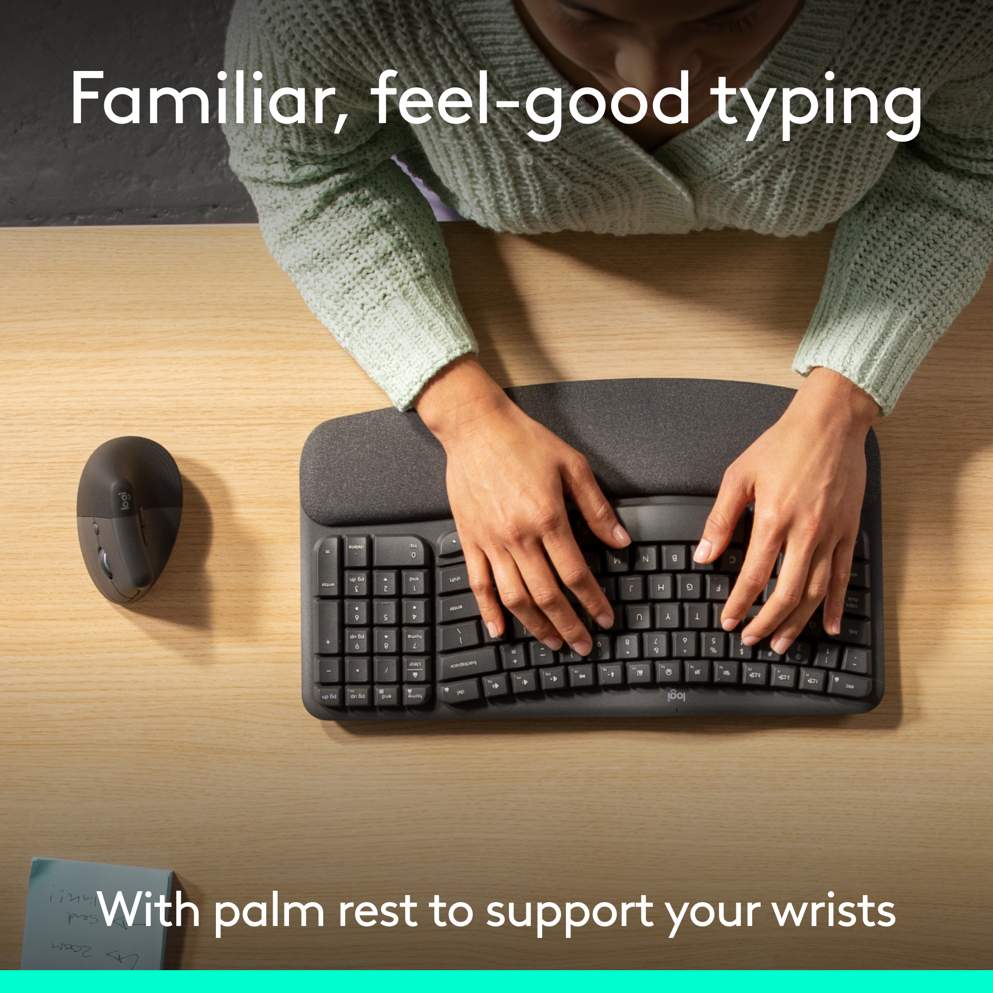 Une personne tape sur un clavier ergonomique noir. Une souris et un post-it sont sur un bureau en bois. Texte : « frappe familière et agréable ».