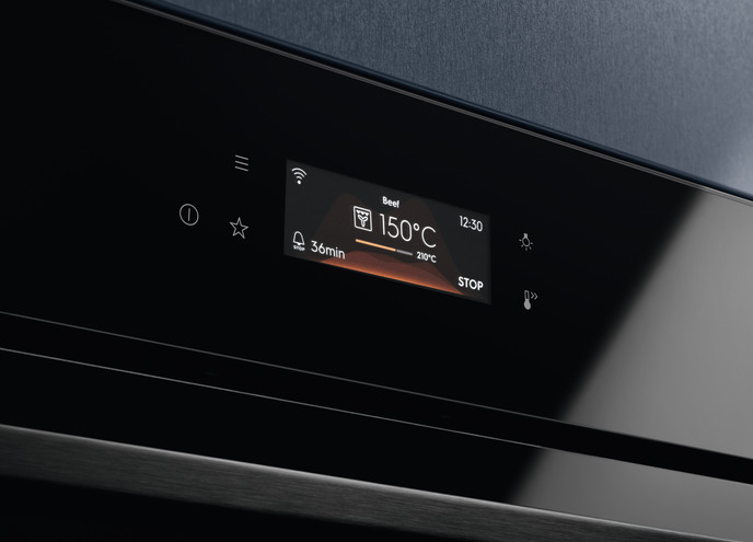 Zbliżenie panelu sterowania piekarnika, wyświetlającego 'Wołowina' w temp. 150°C przez 36 minut. Czas to 12:30. Piekarnik jest czarny.