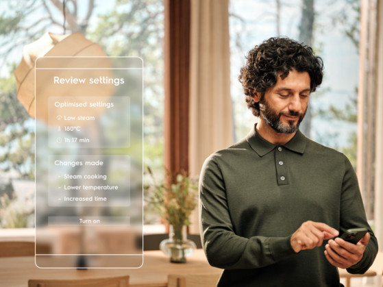 Mężczyzna w zielonej koszuli używa telefonu, przeglądając ustawienia gotowania na parze.