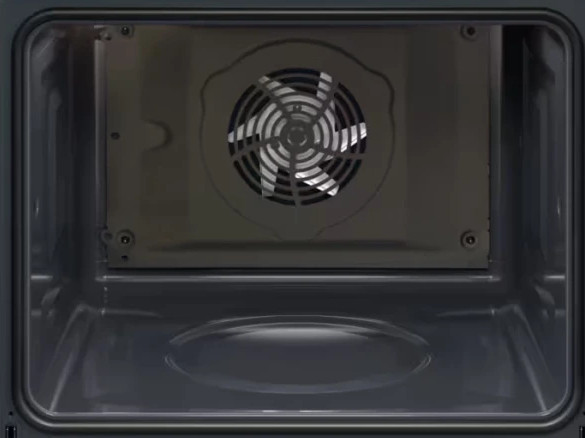 Wewnątrz ciemnego piekarnika z tyłu widoczny jest wentylator. Wnętrze piekarnika jest szare. Na dole znajduje się owalny kształt.