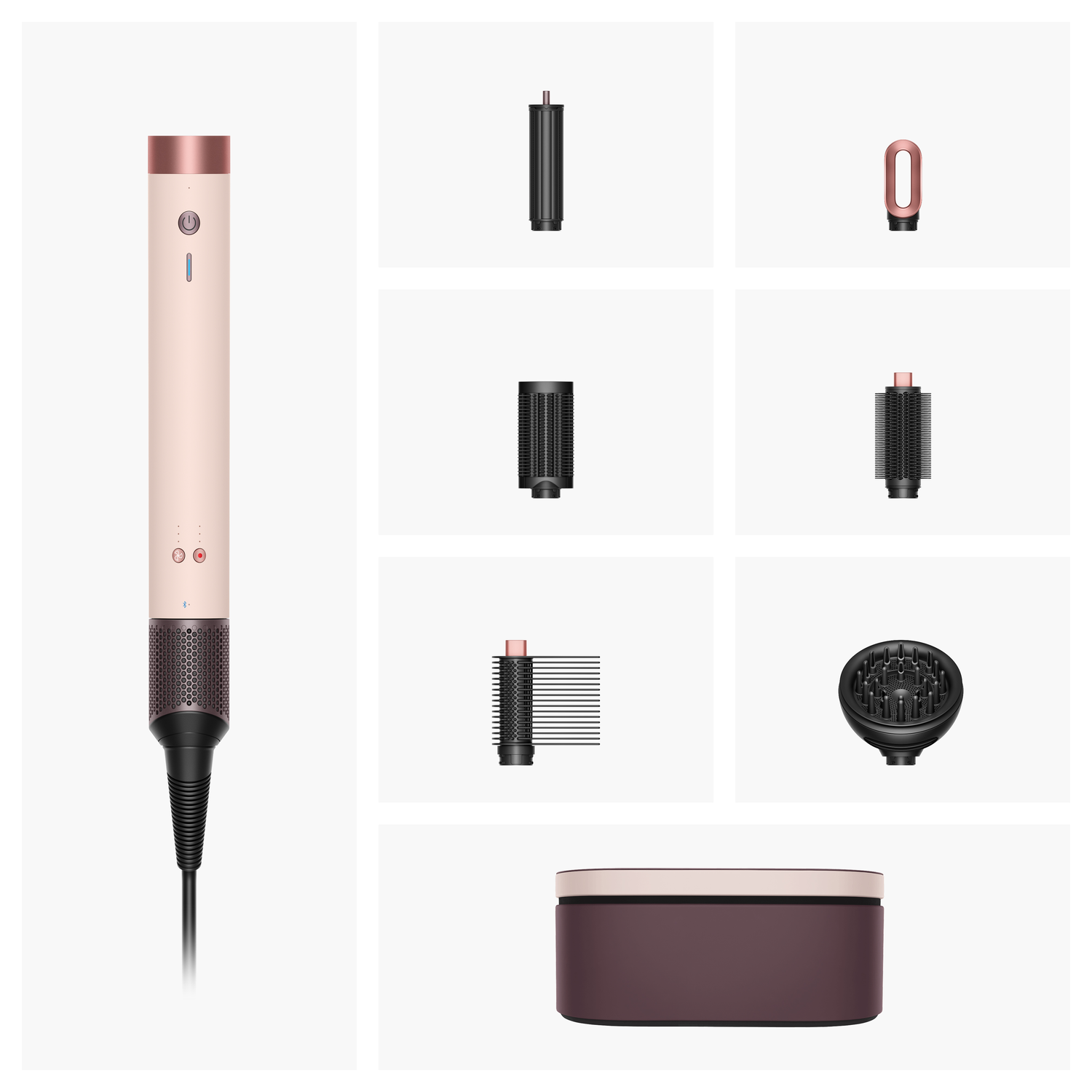 A rose gold hair styling tool with multiple attachments: cylindrical, round brushes, and a diffuser. Also includes a storage case.