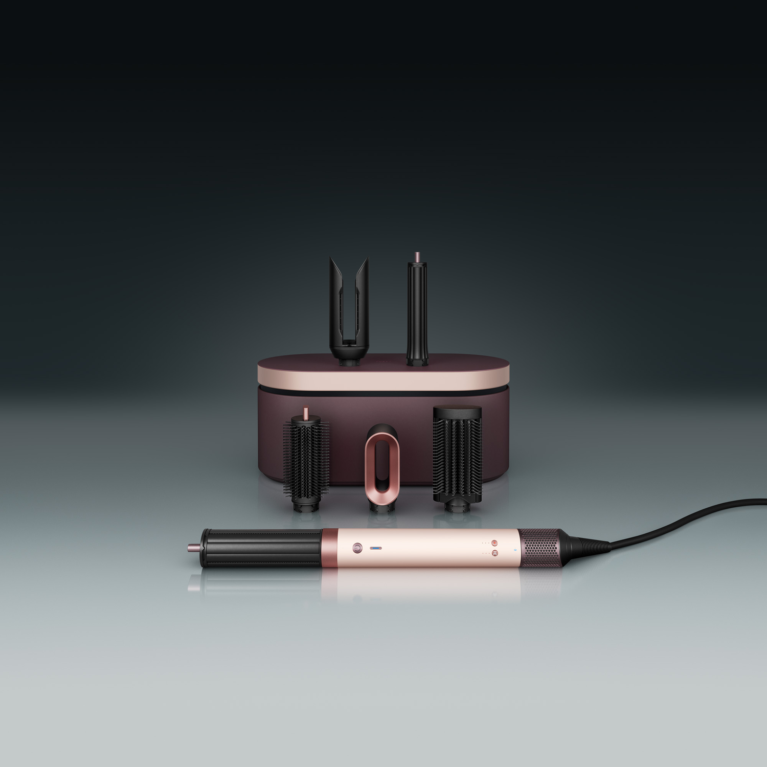 A hair styling set with a pink and black color scheme. Includes a hair dryer, attachments, and a case, all on a reflective surface.