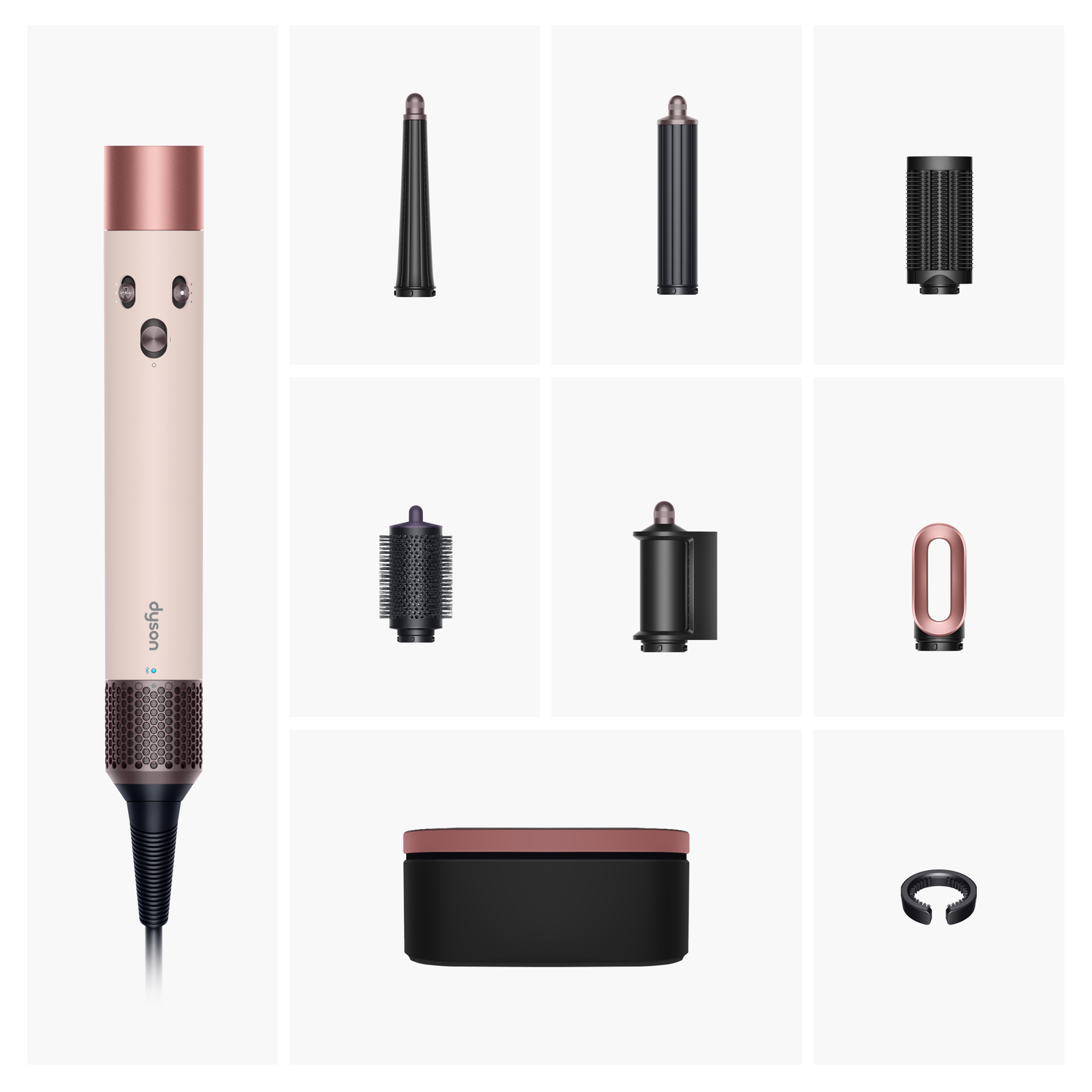 A Dyson hair styling tool with attachments. It includes the main unit, various nozzles, a storage box, and a ring-shaped accessory.