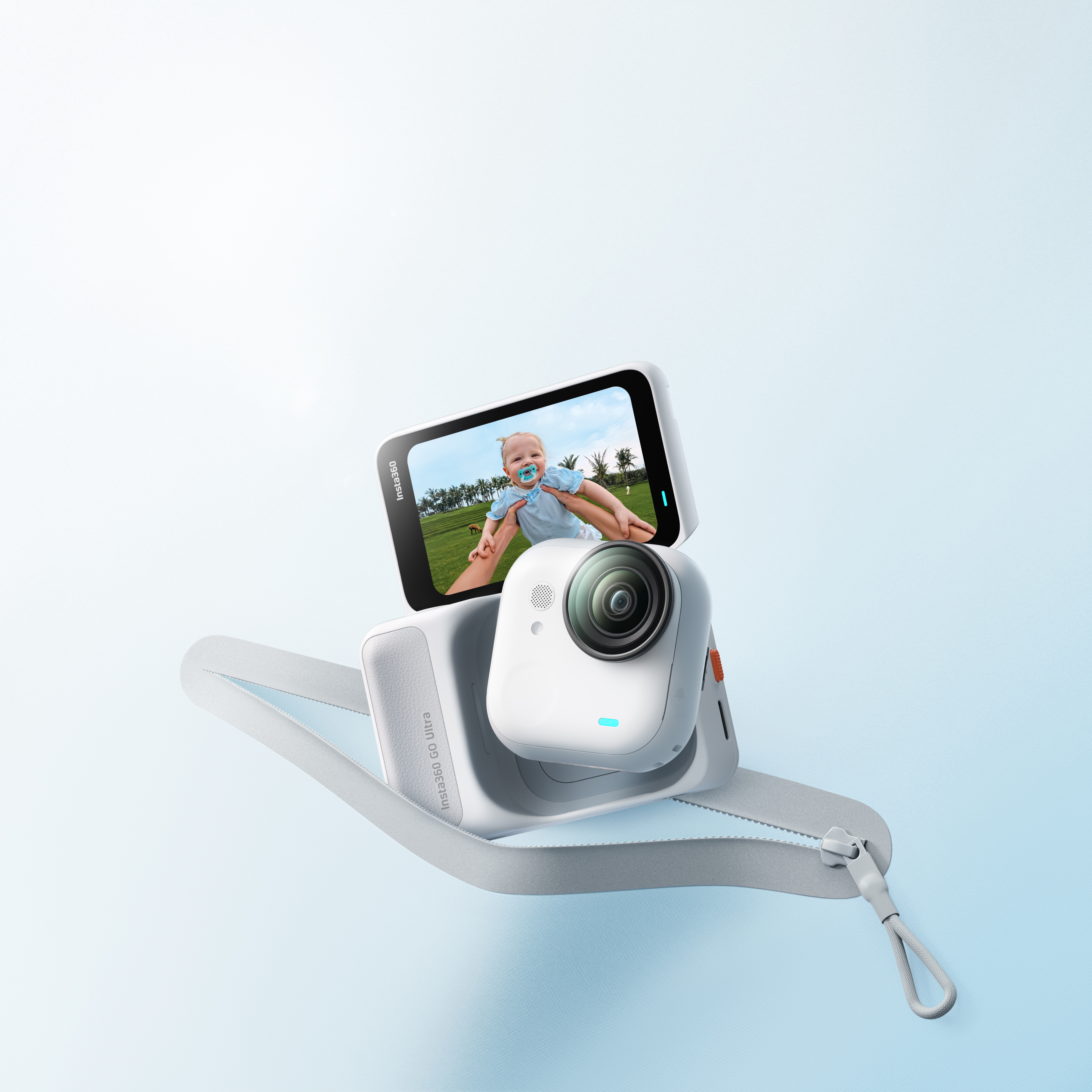 Eine weiße Insta360 Go Ultra Kamera mit Bildschirm, der ein Baby zeigt. Es ist an einem grauen Gurt. Blauer Hintergrund.
