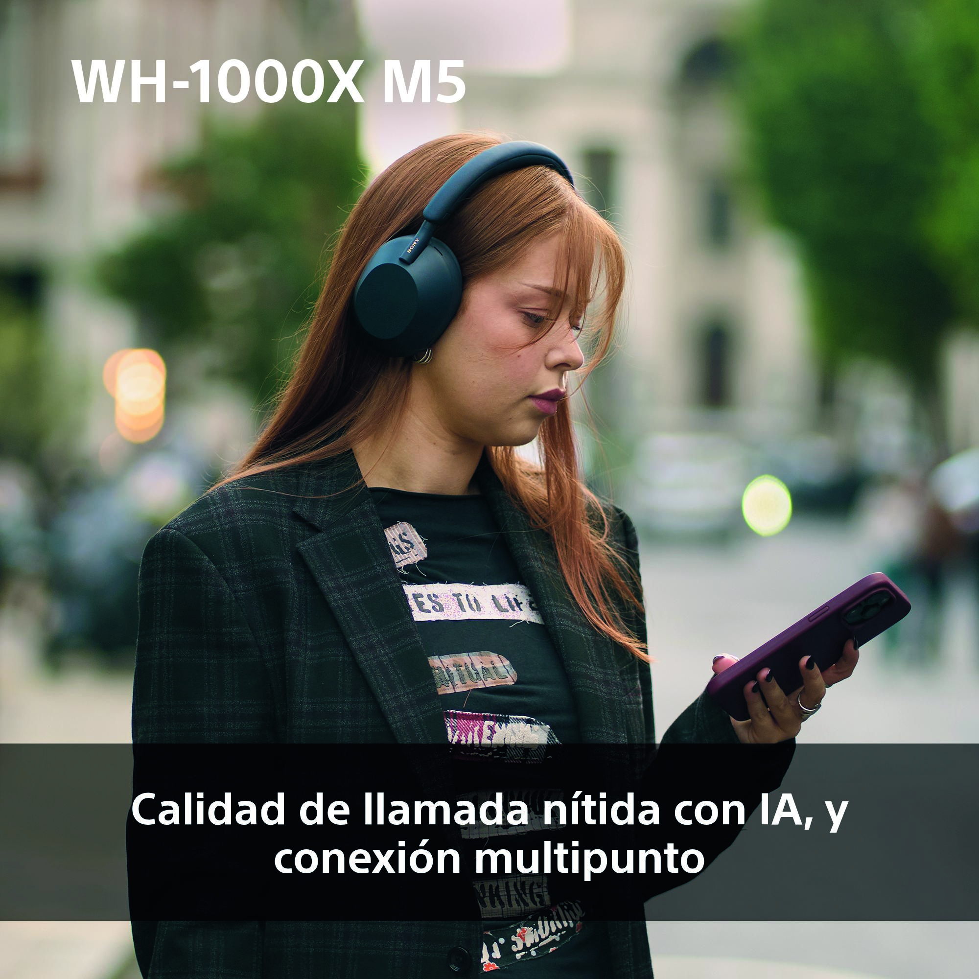 Una mujer con auriculares mira su teléfono. El texto superior dice 'WH-1000X M5'. El teléfono está en su mano derecha.