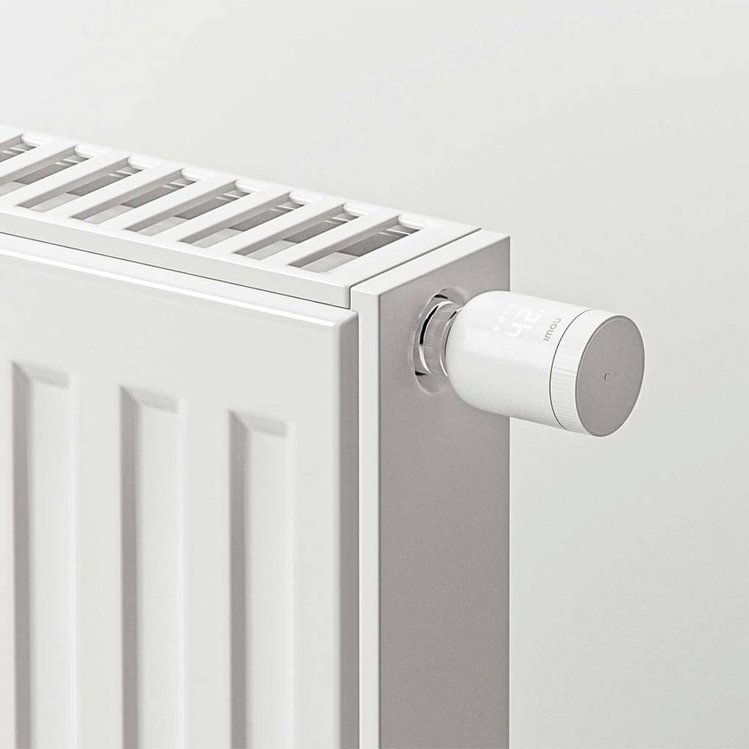 A white radiator with a digital thermostat attached. The thermostat displays '24'. The scene is minimalistic.