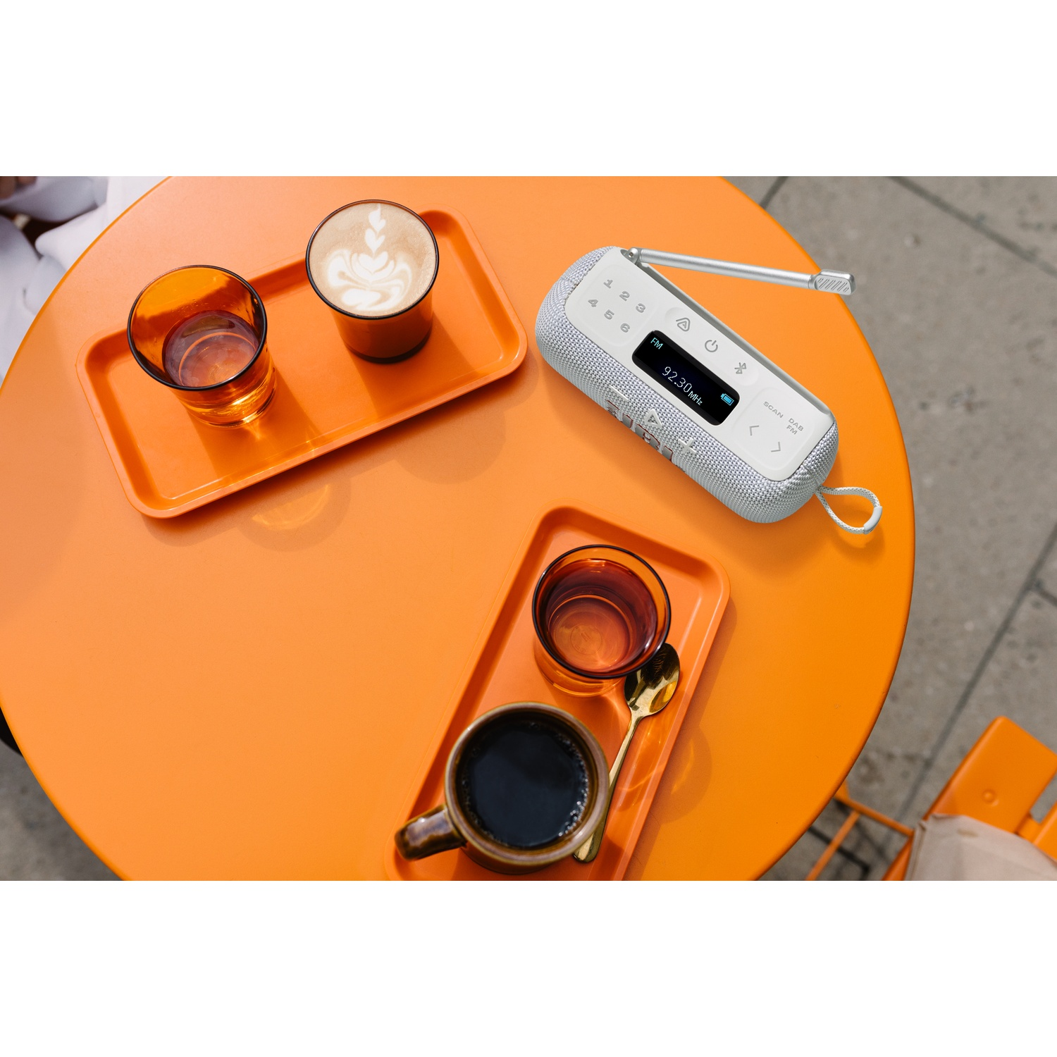 Orange table with coffee, drinks, and a radio. Two trays with coffee and water glasses. A small white radio is on the table.