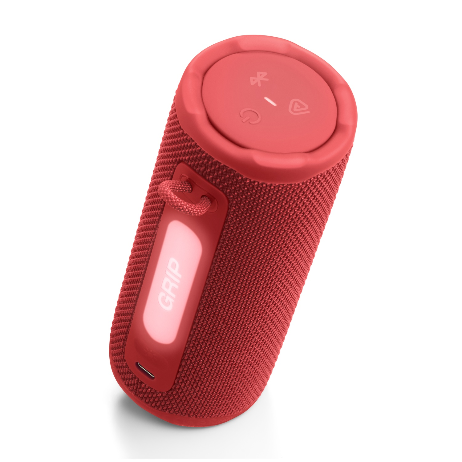 Une enceinte cylindrique rouge sur une surface blanche. Elle a une poignée et des boutons en haut. L'enceinte est étiquetée 'GRIP'.