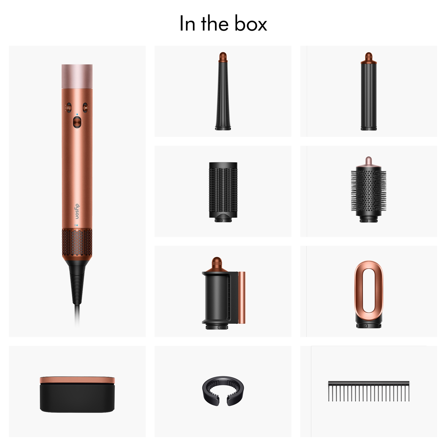 A Dyson hair styler and various attachments in a white setting. The styler is copper and black. Attachments include nozzles and brushes.
