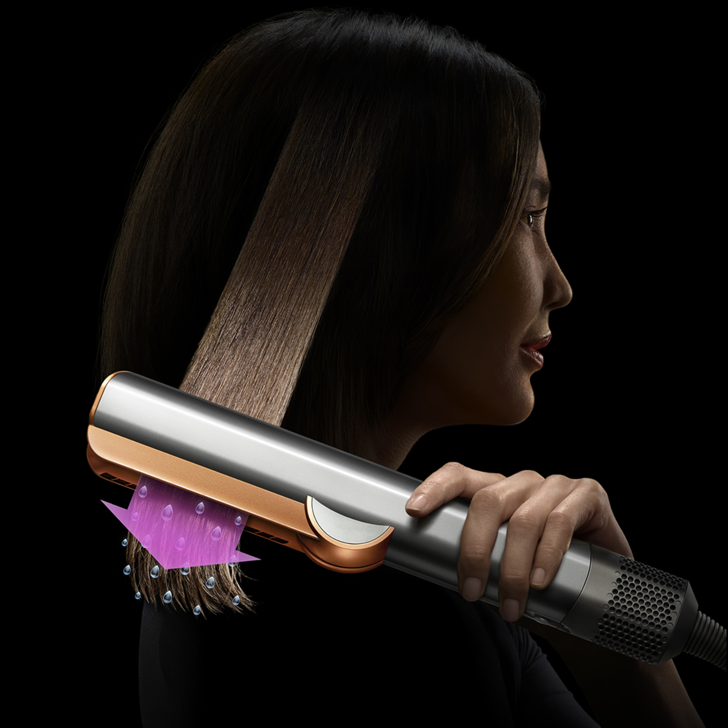 Een vrouw gebruikt een zilver-gouden haarstyler. De styler heeft een paarse luchtstroom. Haar is glad aan de rechterkant.