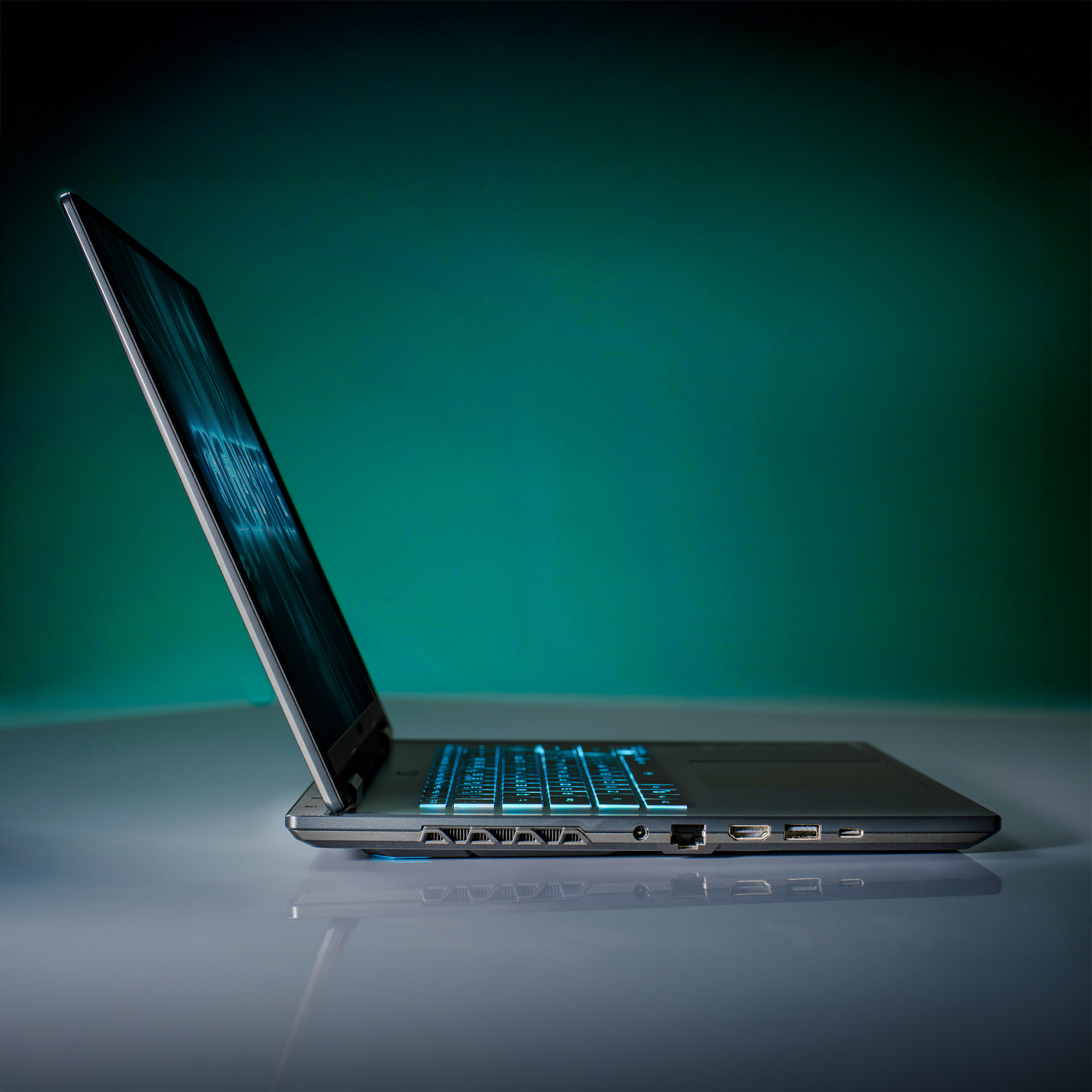 Ein Laptop ist auf einer reflektierenden Oberfläche geöffnet. Der Bildschirm zeigt Licht, und die Tastatur ist hintergrundbeleuchtet. Der Hintergrund ist teal.