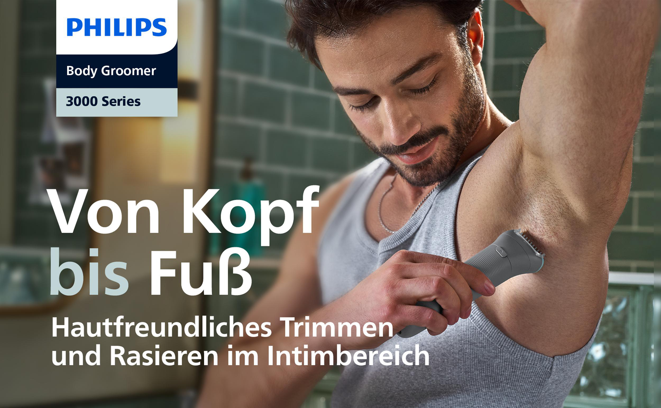 Ein Mann rasiert seine Achselhöhle mit einem Philips Body Groomer. Das Produkt ist grau, der Hintergrund ein Bad.