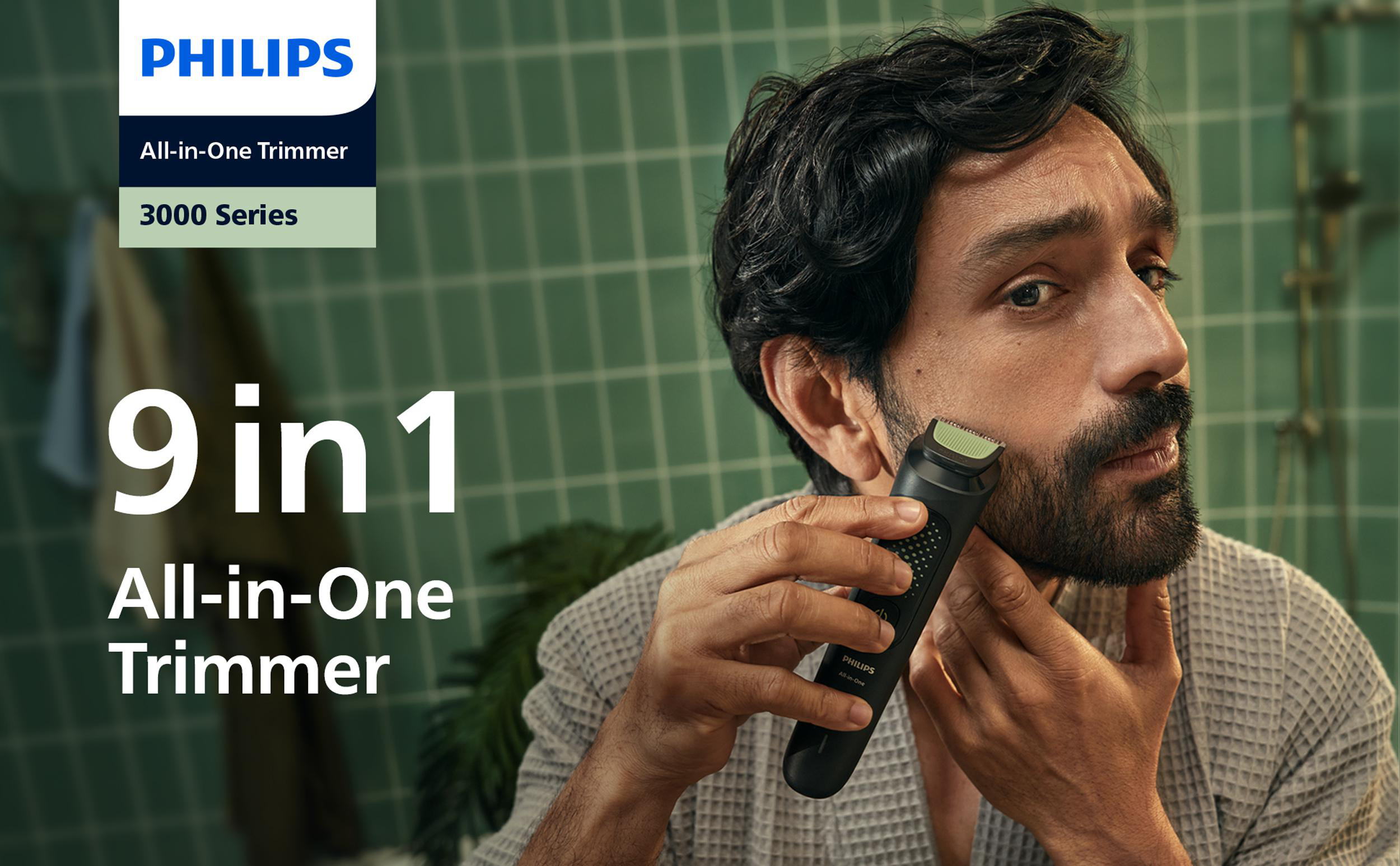 Ein Mann rasiert sich mit einem Philips Trimmer. Der Hintergrund ist eine geflieste Wand. Text: '9 in 1 All-in-One Trimmer'.