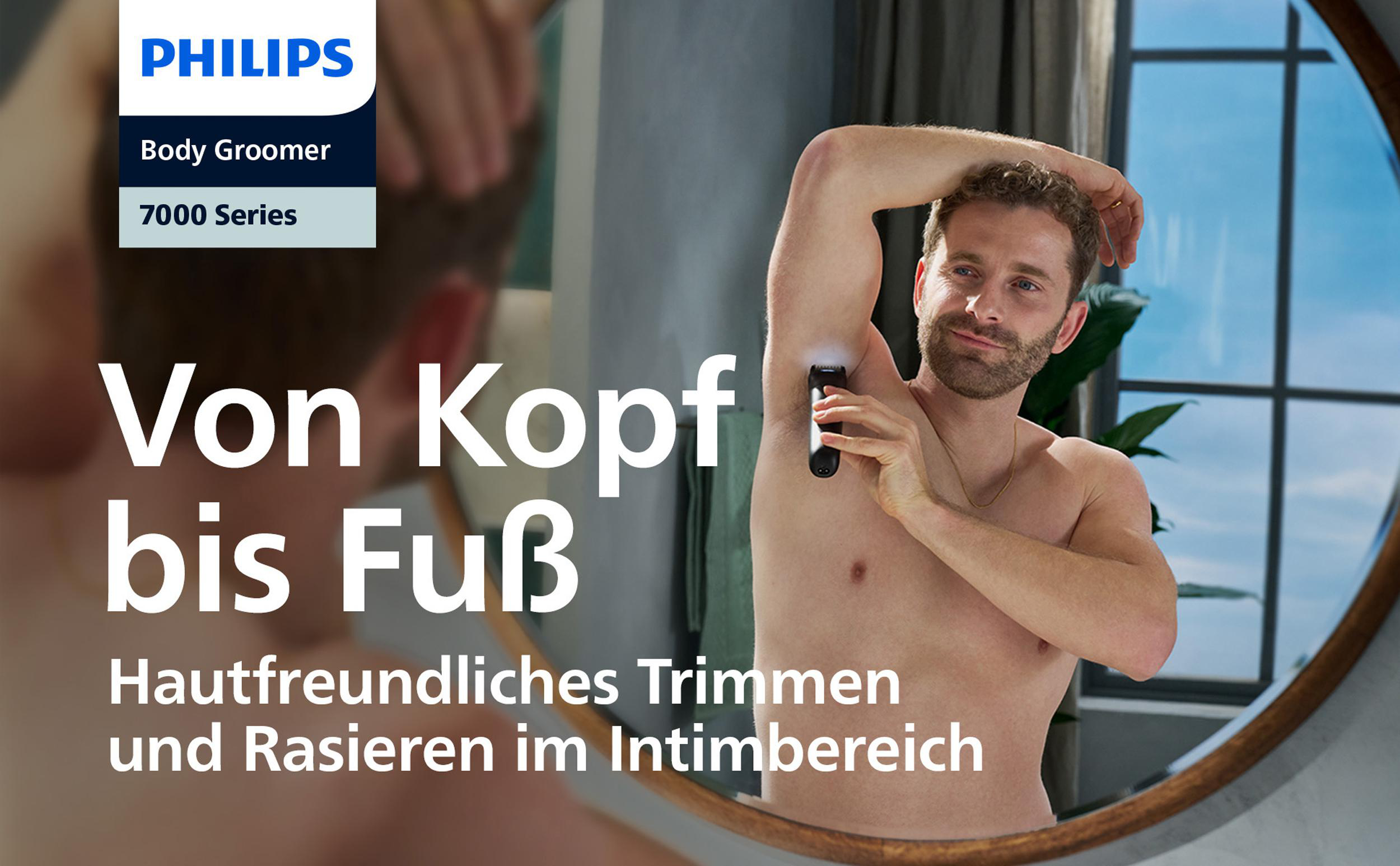 Ein Mann rasiert sich mit einem Philips Body Groomer die Achselhöhle. Der Hintergrund zeigt ein Fenster und einen Spiegel.