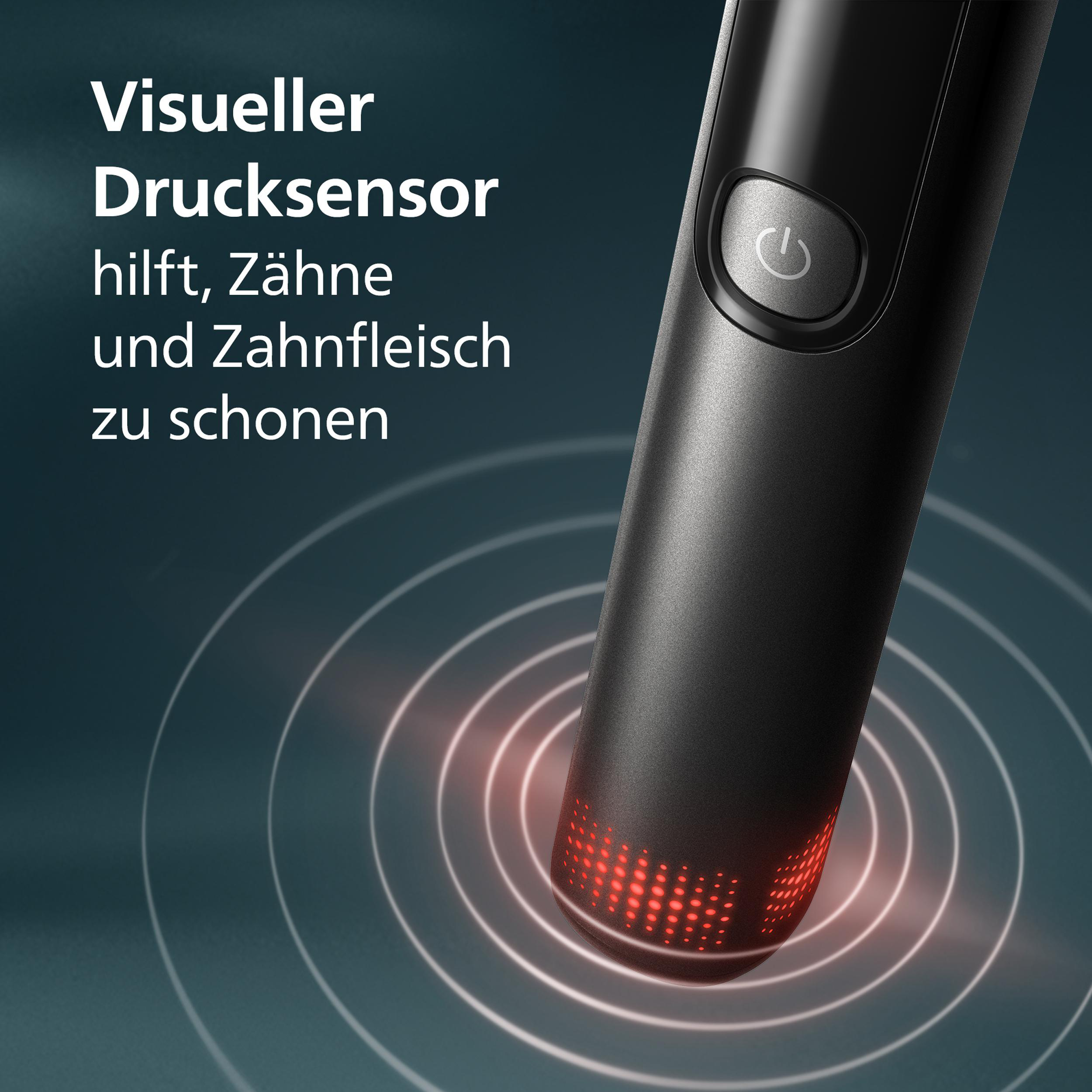 Nahaufnahme eines schwarzen Geräts mit Ein/Aus-Taste. Rotes Licht unten, mit Kreisen. Text auf Deutsch.