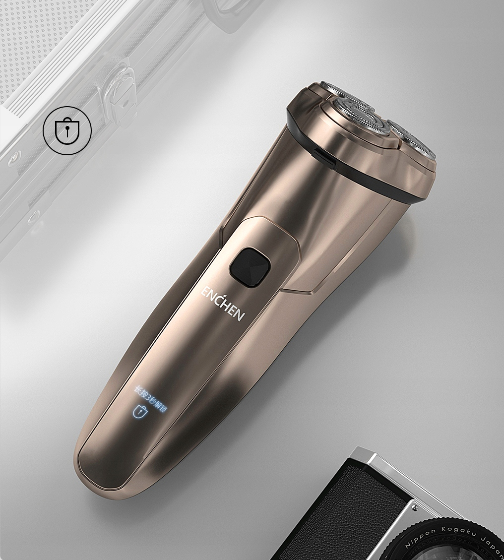 Złota golarka elektryczna z trzema głowicami obrotowymi, czarnym przyciskiem i małym ekranem leży na szarej powierzchni.