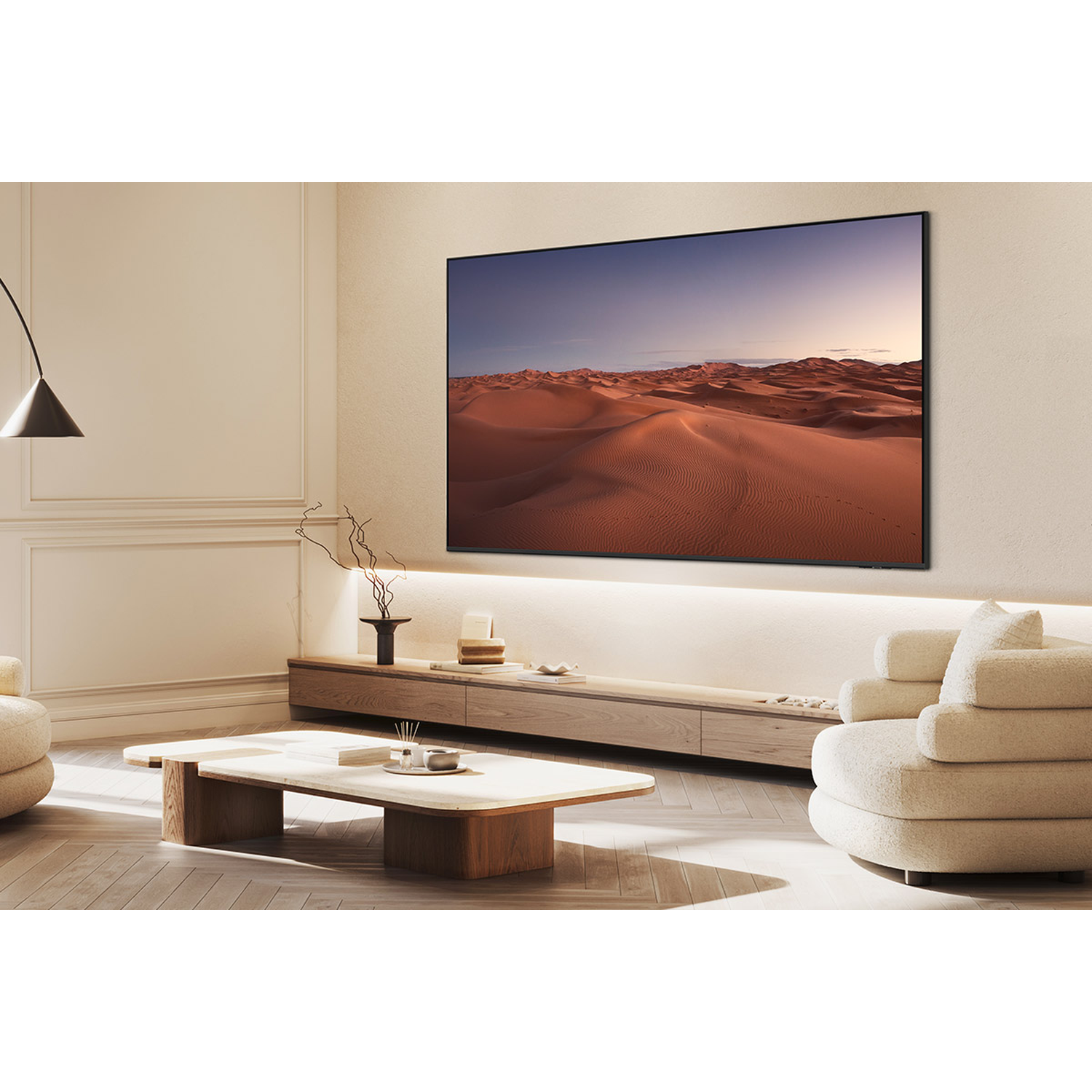 Een moderne woonkamer met een grote tv met een woestijnlandschap. Beige meubels en een houten salontafel op de voorgrond.