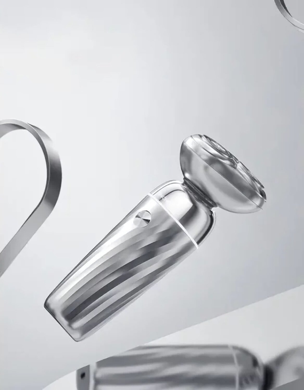 Srebrna golarka elektryczna. Jest ustawiona pod kątem i ma teksturowany uchwyt. Tło jest białe z rozmytymi srebrnymi kształtami.