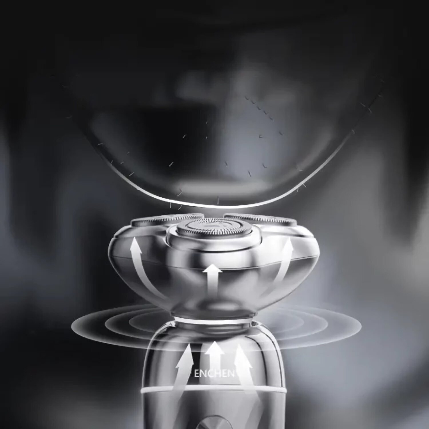 Zbliżenie golarki elektrycznej. Strzałki wskazują ruch. Golarka ma chromowane wykończenie, tło jest szare i rozmyte.