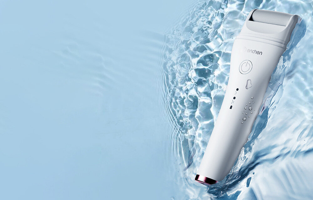 Białe urządzenie do pielęgnacji stóp jest częściowo zanurzone w wodzie. Ma przycisk zasilania i wskaźniki. Tło to niebieska woda.