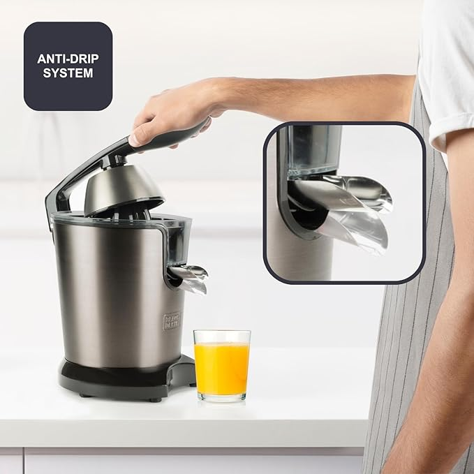 Osoba używa srebrnej wyciskarki do cytrusów. Szklanka soku pomarańczowego stoi na blacie. Wstawka pokazuje system antypoślizgowy.