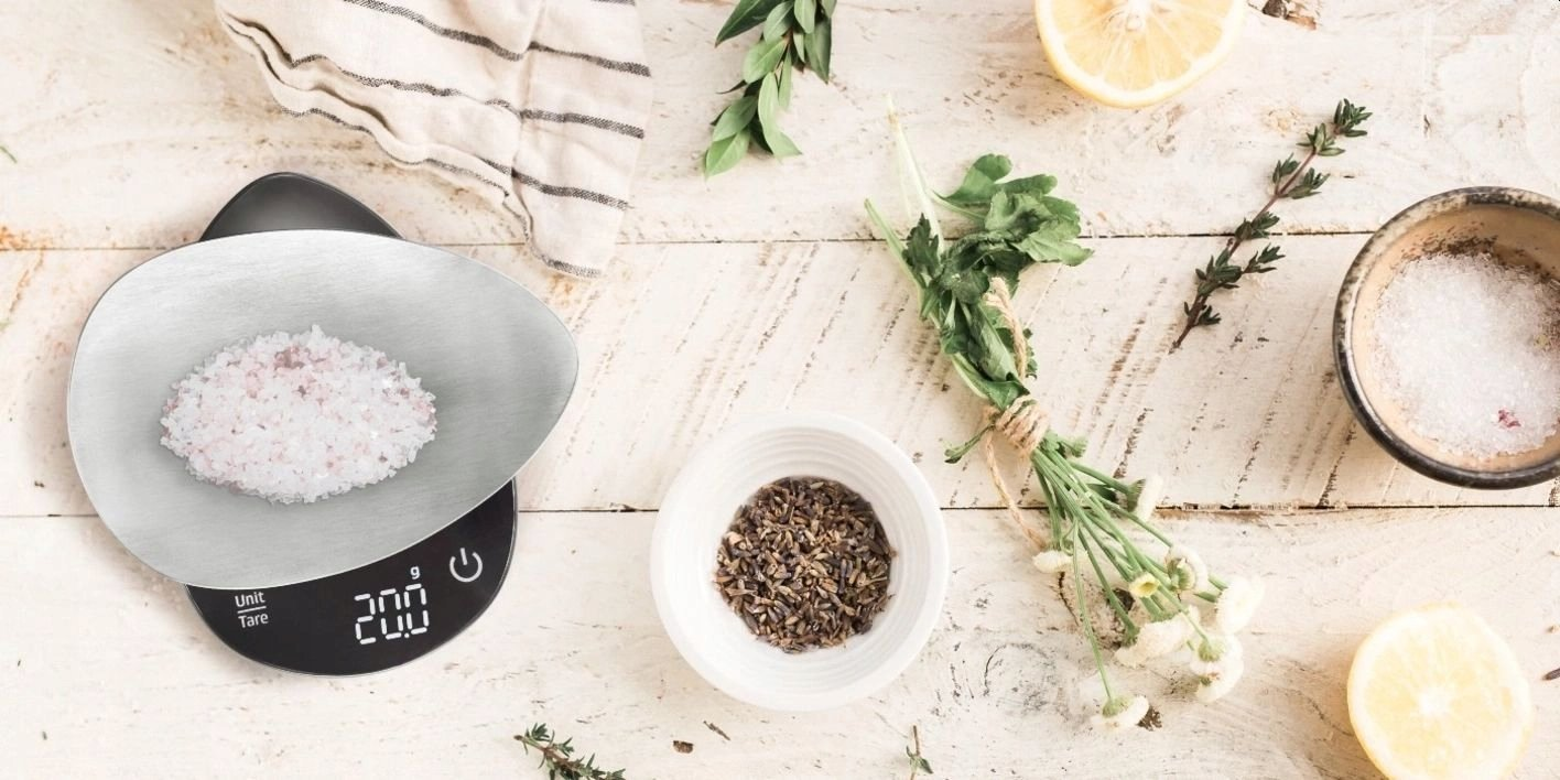 Waga z różową solą, ziołami, przyprawami i plasterkami cytryny na rustykalnej drewnianej powierzchni. Składniki do gotowania ułożone.