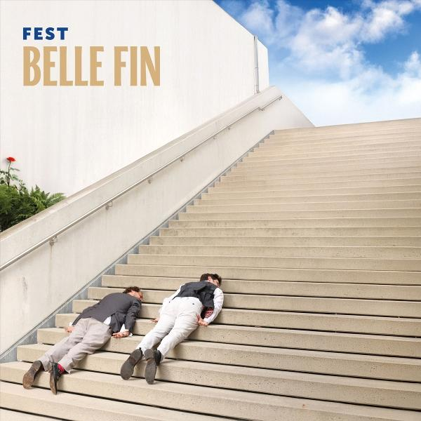 Zwei Männer liegen auf einer Betontreppe. Darüber ist der Himmel blau. Das Wort 'FEST BELLE FIN' steht auf der weißen Wand.
