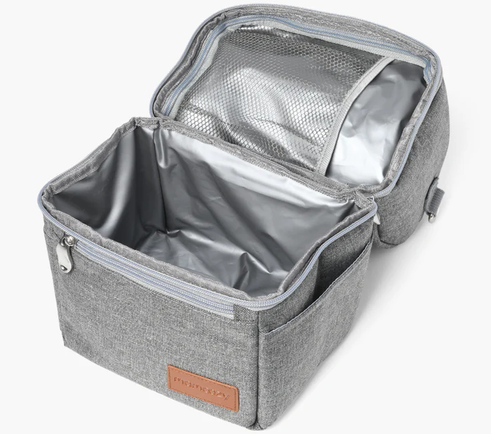 Geöffnete graue isolierte Lunchtasche. Innen silbernes Futter, Netztasche und ein kleiner Beutel. Braunes Etikett mit der Aufschrift 'momcozy'.