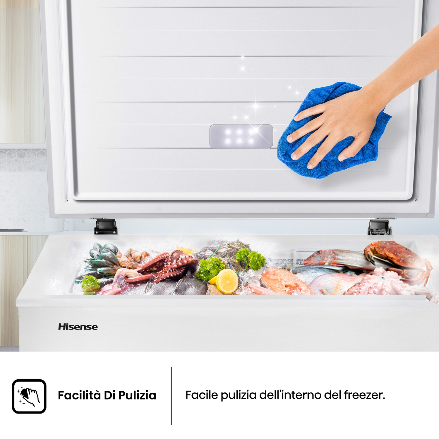 Una mano con un panno blu pulisce un congelatore bianco. Il congelatore è aperto, mostrando frutti di mare. Logo Hisense.