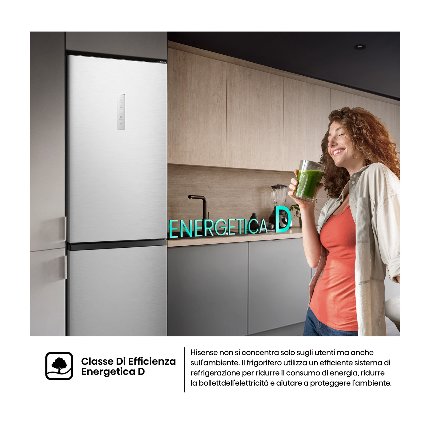 Una donna sorride tenendo una bevanda verde accanto a un frigorifero d'argento. Il frigorifero ha un'etichetta di efficienza energetica. Lo sfondo è una cucina.