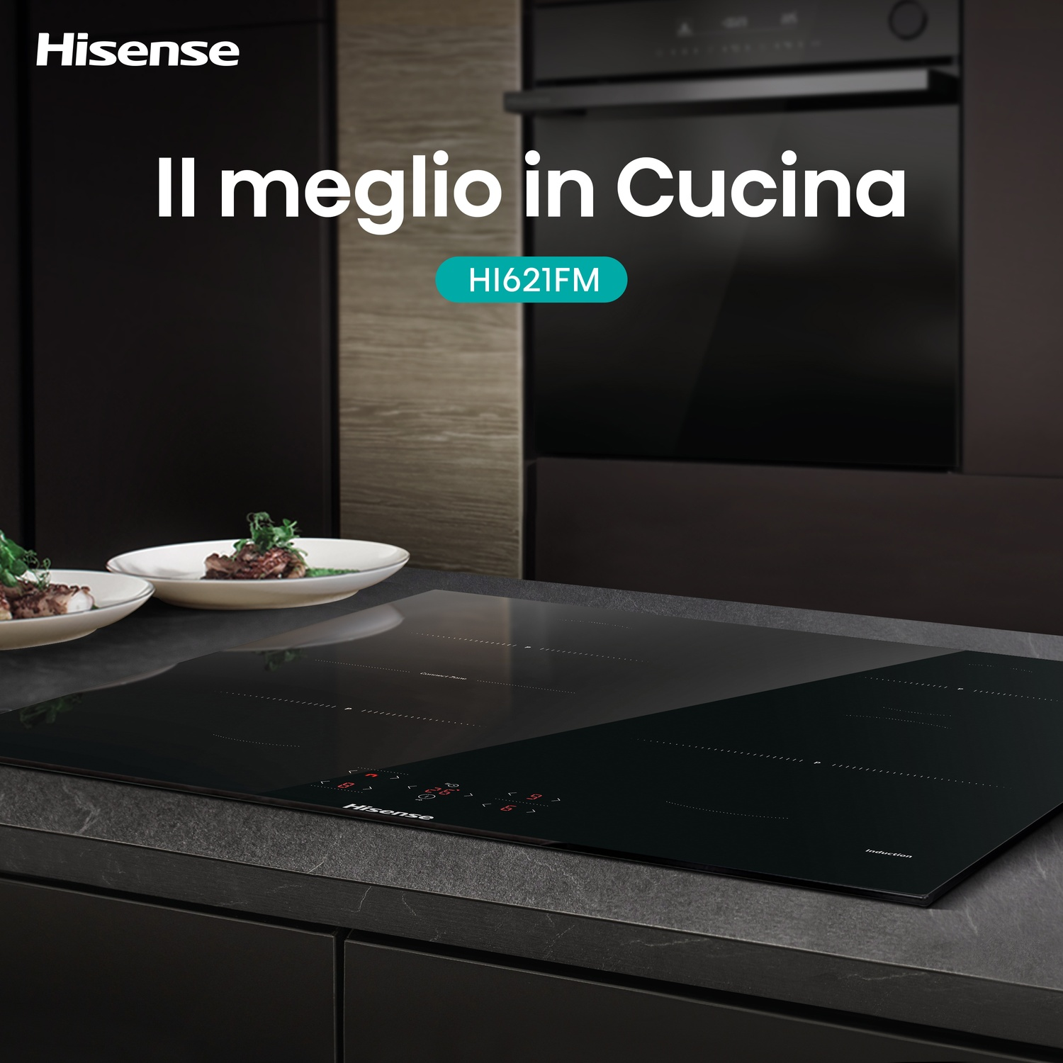 Piano cottura a induzione Hisense nero in una cucina. Due piatti con cibo sul bancone. Forno sullo sfondo. Il testo recita 'Il meglio in Cucina'.