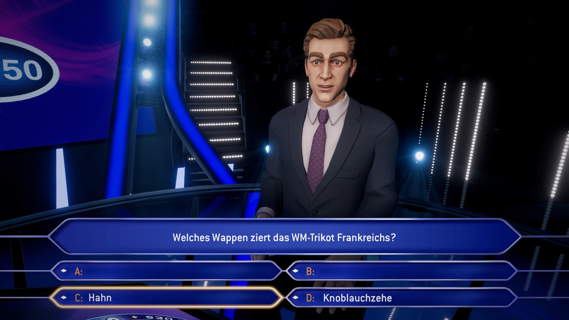 Ein Spielshow-Moderator im Anzug steht vor einem Bildschirm mit einer Frage zu einem Fußballtrikot. Die Optionen umfassen Hahn und Knoblauchzehe.