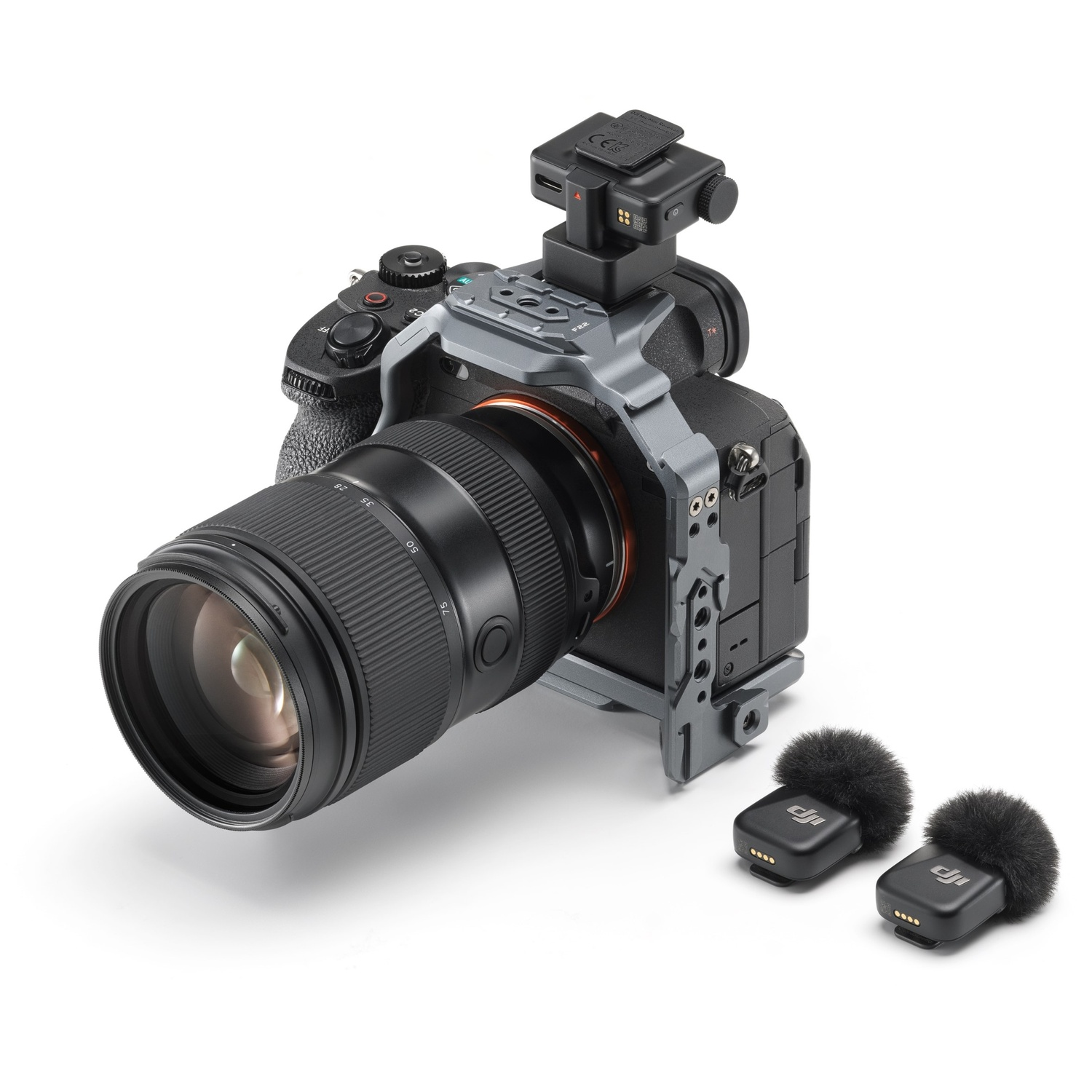 Een digitale camera met lens. Twee microfoons eronder. Een kooilijst om de camera. Alles op een wit oppervlak.